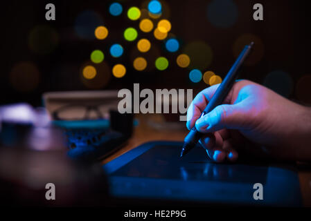 Graphic designer holding a pen over tablet. Stock Photo