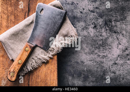 Butcher. Vintage butcher meat cleavers with cloth towel on dark concrete or wooden kitchen board. Stock Photo