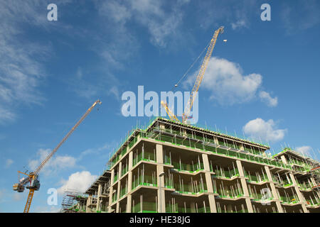 Pair of construction cranes on top of a new building. Blue sky and white clouds Stock Photo