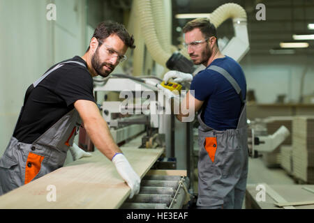 Young male workers work in a factory for the production of furniture Stock Photo