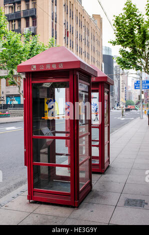 Red telephone box booth on downtown sidewalk The Bund, Shanghai, China. Stock Photo