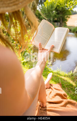 woman with golden hair reading book in nature in summer Stock Photo