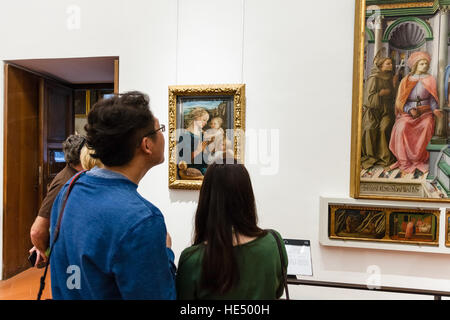 FLORENCE, ITALY - NOVEMBER 5, 2016: tourists view painting in room of Uffizi Gallery. The Uffizi is one of the oldest museums in Europe, its origin re Stock Photo