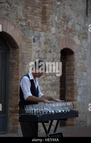 Busker playing classical music on water filled wine glasses, San Gimignano, Italy Stock Photo