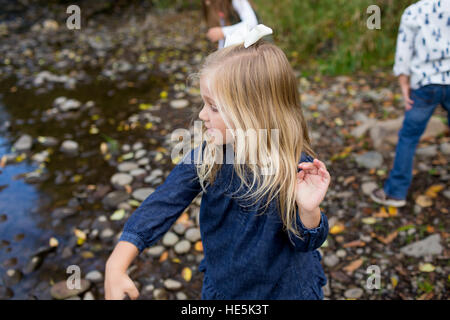 Siblings throw rocks in the McKenzie River together in the lifestyle shot of the children having fun playing. Stock Photo