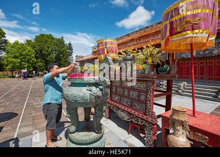 Man lights up an incense stick at The To Mieu Temple. Imperial City (The Citadel), Hue, Vietnam. Stock Photo