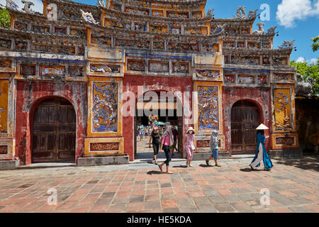 Tourists walking through a gate in the The To Mieu Temple Compound. Imperial City (The Citadel), Hue, Vietnam. Stock Photo