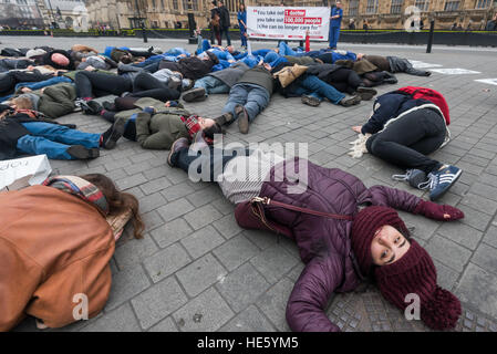 London, UK. 17th December 2016. Healthcare workers hold a die-in at Parliament in solidarity with the Syrian people, calling for an end to the bombing of civilians, hospitals and schools and for the UK to pressure the Syrian government to allow the delivery of aid. They urge the UK to make airdrops of aid, provide safe passage to all those trapped and grant asylum to refugees. The protest was organised by Medact's Arms and Militarisation (MAM) group with Syria solidarity activist groups and individuals including the Syrian British Medical Society. Peter Marshall/Alamy Live News Stock Photo