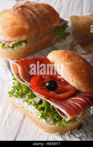 Delicious sandwiches with fresh vegetables and prosciutto on white ...
