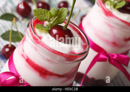 soft cream with a fresh cherry in a glass jar macro. horizontal Stock Photo