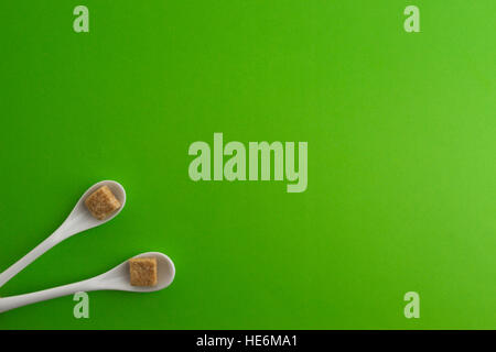 https://l450v.alamy.com/450v/he6ma1/two-white-spoons-with-brown-sugar-cubes-placed-in-a-corner-of-composition-he6ma1.jpg