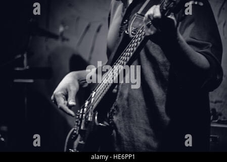 Electric bass player playing guitar on stage, close-up - black & white Stock Photo