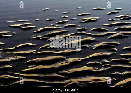 sand ripples on the beach highlighted by evening light  and the incoming sea Stock Photo