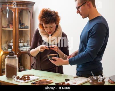 Young men and women are preparing chocolate truffles in a shop Stock Photo