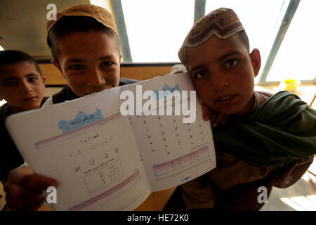 A young Afghan boy leans over his desk to show off his school book, March 31, Morgan Kacha village, Southern Afghanistan. U.S. Army and Afghan national army soldiers visited the village to deliver school supplies for children and to conduct counterinsurgency operations. Stock Photo