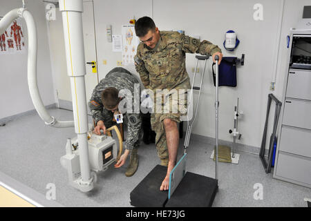 U.S. Army Sgt. Karl Berlinger (right) prepares for an X-ray of his right foot with assistance from Spc. Jesse Stroman, radiology technician, Feb. 12, 2014, Landstuhl Regional Hospital, Germany.  Berlinger and his unit were on their way back to Kandahar Airfield, Afghanistan, after a perimeter patrol when they got hit by an improvised explosive device, which blasted the vehicles door inward slamming across Berlinger's right foot. (U.S. Force photo/Senior Airman Chris Willis) Stock Photo