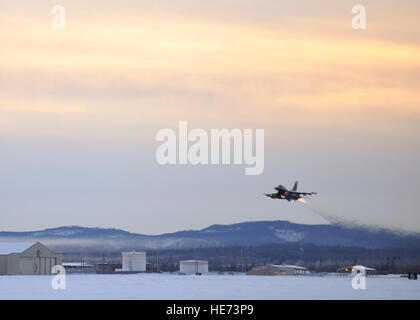 One of 14 U.S. Air Force F-16 Fighting Falcon aircraft with the 18th Aggressor Squadron takes off from Eielson Air Force Base, Alaska, shortly after sunrise Jan. 17, 2015, in transit to Hickam Air Force Base, Hawaii and Andersen Air Force Base, Guam, to participate in the Century Aloha and Cope North exercises. More than 150 maintainers will keep the Aggressors in the air during the exercises, which are meant to prepare U.S. Airmen, Sailors and Marines along with coalition partners in the Pacific theater of operations for contingency operations if the need arises.  Master Sgt. Karen Tomasik Stock Photo