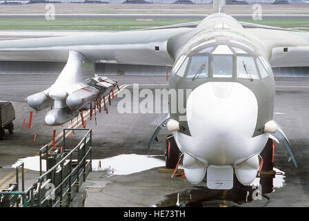 A specially-designed remote control hydraulic trailer is removed from under the wing of a 92nd Bomb Wing B-52G Stratofortress aircraft.  The trailer was used to attach a pylon carrying six AGM-86B air-launched cruise missiles (ALCM), background, to the wing of the aircraft. Stock Photo