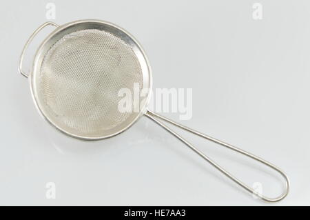 handheld colander tool on reflective white background Stock Photo
