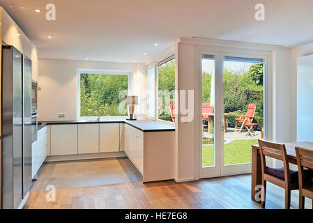 modern kitchen in renovated house with view on dining table with chairs in a lush garden Stock Photo