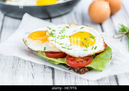 Wooden table with Fried Eggs (on a Sandwich) as detailed close-up shot Stock Photo