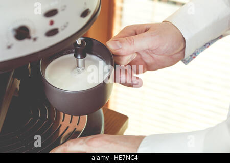 Man is foaming milk in a coffee machine. Retro photo effects Stock Photo