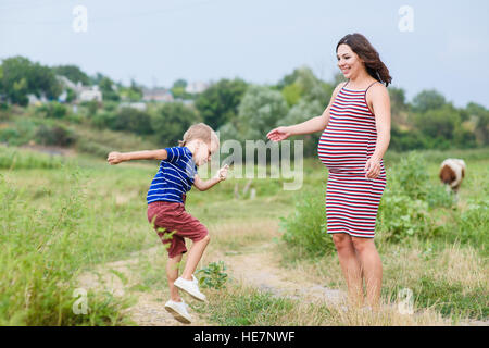 Pregnant woman walking countryside with her son. Happy mother and her son Stock Photo