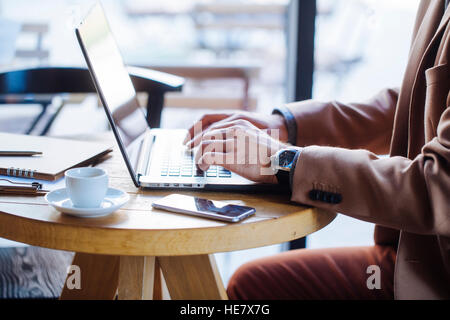 Unrecognizable Businessman Typing on Laptop in Coffee Shop Stock Photo