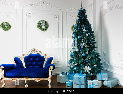 Large Christmas tree with a lot of presents and different decorations in the room in classic style with vintage sofa in baroque style Stock Photo