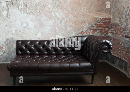 Leather sofa in the English style in the room with old red brick walls Stock Photo