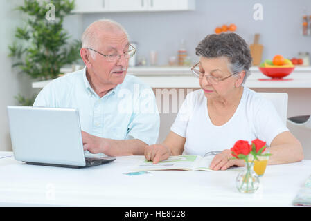 Wife looking at magazine, husband on laptop Stock Photo