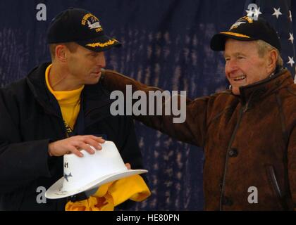 U.S. Navy Commanding Officer Kevin O'Flaherty presents former U.S. President George H.W. Bush with a yellow jersey and cowboy-style hard hat as gifts after dead load launches off the flight deck of the USN Nimitz-class aircraft carrier USS George H.W. Bush January 25, 2008 in Newport News, Virginia. Stock Photo