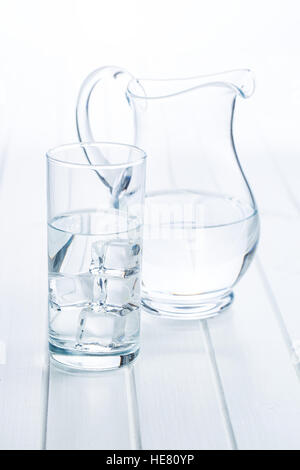 Glass of pure water with ice cubes on white table. Stock Photo