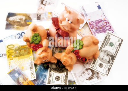 Pigs as a symbol of good luck with various currency banknotes Stock Photo