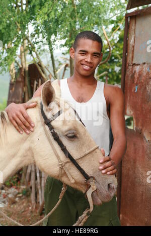 Young smiling man standing next to his horse, Trinidad, Sancti-Spiritus Province, Cuba, Latin America Stock Photo