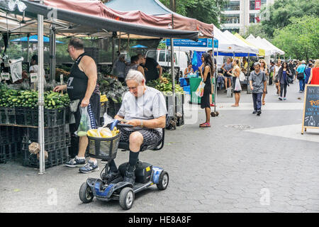 sporty disabled senior man sits in swivel chair seat of Go-Go Sport 4 wheel electric scooter shopping Union Square like everyone Stock Photo