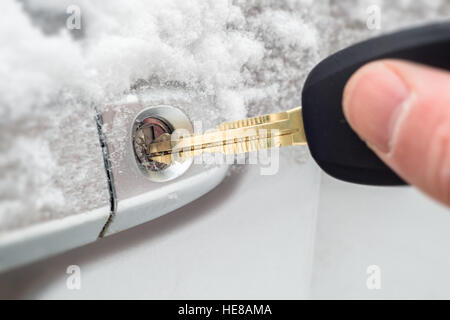 Close-up of a key inserted into the lock of frozen car door in winter Stock Photo