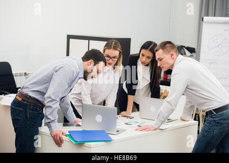 Young business people sitting in office during meeting and discussing with paperwork using laptops Stock Photo