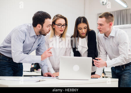 Colleagues at an office meeting talking and working on a laptop Stock Photo