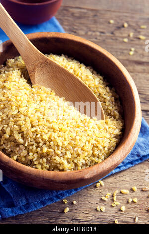 Organic bulgur, couscous  raw wheat grain in ceramic bowl close up - healthy food ingredient Stock Photo