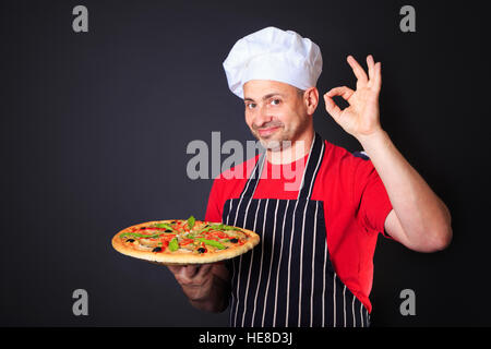 Portrait of happy attractive cook with a pizza in his hands Stock Photo