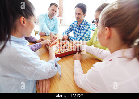 Friends taking slices of pizza from the box Stock Photo