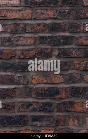 Aged uneven red and brown brick wall, blackened with wide brown lines of pointing Stock Photo