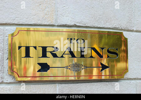 Public transportation, close-up of brass plate sign on railway station indicating direction to board trains, railway transportation, USA Stock Photo