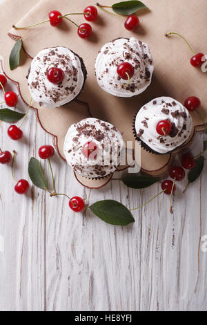 Chocolate cupcakes with cream and fresh cherry Black Forest on the table. vertical top view Stock Photo