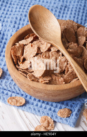 Healthy breakfast: Bran flakes in a wooden bowl closeup. Vertical Stock Photo
