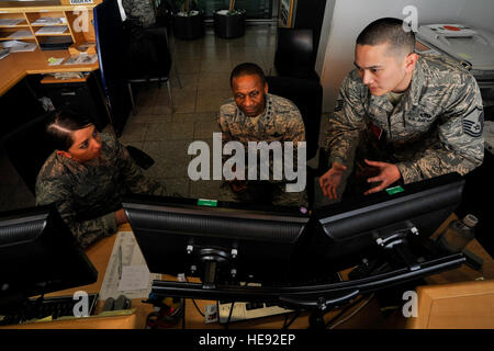 Gen. Darren W. McDew, Air Mobility Command commander, receives a briefing on passenger processing from Senior Airman Lindsay Meyer (left), 721st Aerial Port Squadron Ramstein Passenger Terminal service agent, and Master Sgt. Tsoon Lai, 721st APS RST passenger service operations supervisor at Ramstein Air Base, Germany, March 30, 2015. The general not only visited Airmen at Ramstein, but had an opportunity to process a customer through the 721st APS Ramstein Passenger Terminal. Senior Airman Nicole Sikorski) Stock Photo