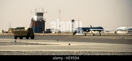 A security forces humvee escorts an MQ-1 Predator onto the runway at a base in southern Afghanistan, Oct. 25. Due to the small size of the aircraft and how unfamiliar many pilots are with it at the NATO-controlled air field, security forces must escort the Predator to prevent potential mishaps.  Staff Sgt. Samuel Morse Stock Photo