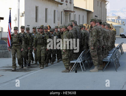 U.S. service members render a salute as a formation of multiservice special operators march with a U.S. flag bearing the names of seven special operators who were killed March 4, 2002, during Operation Anaconda: U.S. Air Force Senior Airman Jason Cunningham, U.S. Army Cpl. Matthew Commons, U.S. Army Spc. Marc Anderson, U.S. Army Sgt. Phillip Svitak, U.S. Army Sgt. Bradley Crose, U.S. Navy Petty Officer 1st Class Neil Roberts and U.S. Air Force Tech. Sgt. John Chapman, March 3, 2015, at Bagram Air Field, Afghanistan. Service members from all branches conducted a 24-hour vigil run and a retreat  Stock Photo