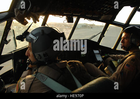 Col. Donald Kimminau, 332nd Expeditionary Operations Group deputy commander, and Capt. Jesse Caldwell, 777th Expeditionary Airlift Squadron aircraft commander, look on as cargo is brought up to the aircraft for loading in Southwest Asia, May 7. The 777 EAS personnel estimate they have prevented approximately 10,000 convoy vehicles and about 27,000 service members from traveling along improvised explosive device laden Iraqi roads since the squadron stood up in January 2006. This was accomplished by providing air transport via C-130 aircraft, the 'work horse' of the Air Force fleet. Kimminau is  Stock Photo